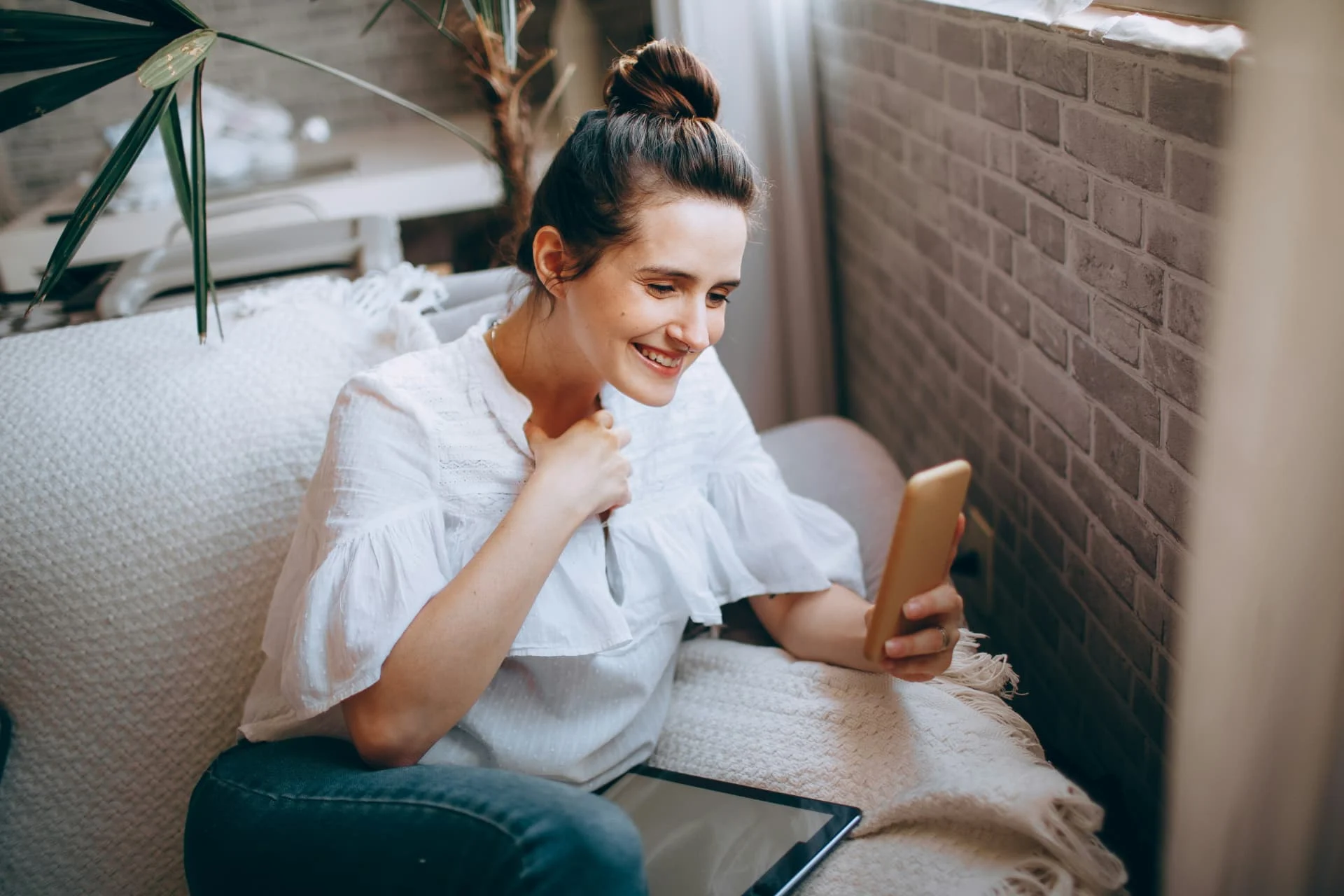 Une femme sourit devant son téléphone, chez elle, pendant un échange avec WoMA